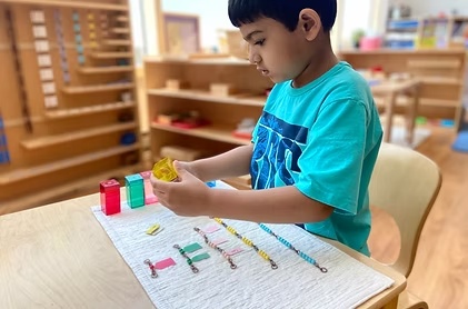 A Mini Me child concentrating on Montessori mathematics work